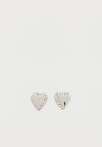 Ασημένια σκουλαρίκια σε σχήμα καρδιάς με στρας να διακοσμούν την άκρη. Γυαλιστερό φινίρισμα με χαραγμένο το κείμενο "GUESS" στην επιφάνεια.