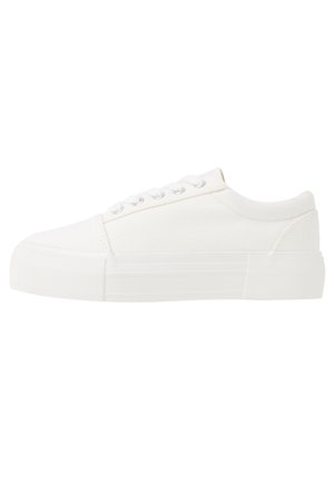 White canvas sneakers with a thick, white rubber sole, featuring a rounded toe and classic lace-up design with five eyelets.