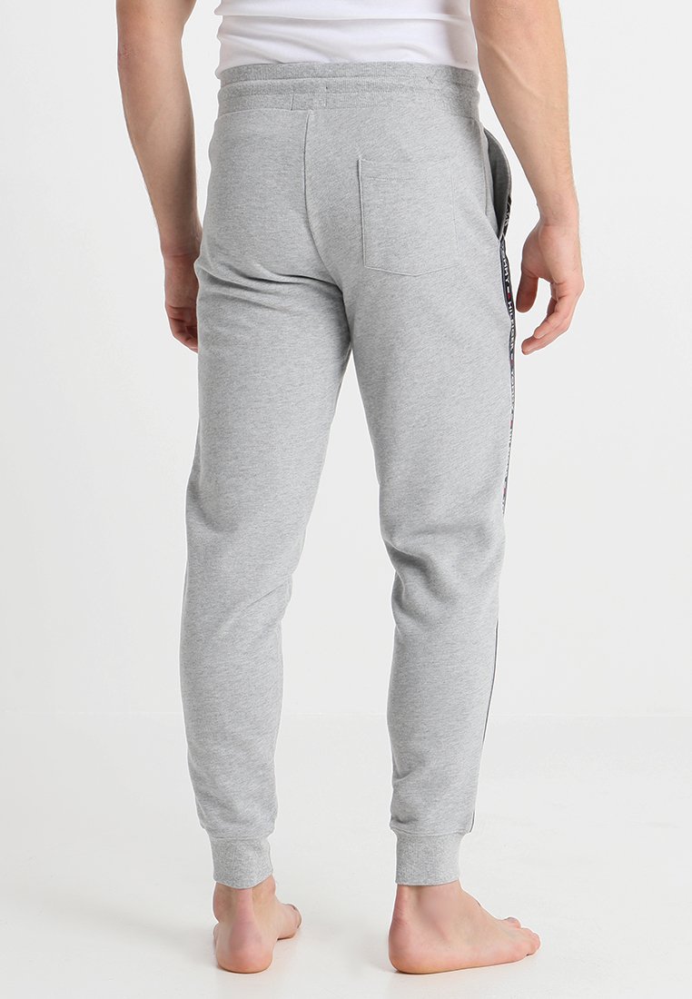 Pantalons de jogging gris en coton avec une coupe ajustée, une taille élastique et des rayures latérales. Inclut une poche arrière et des poignets côtelés.