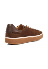 Brown suede sneaker with a dark brown leather heel cap, cream laces, and a tan rubber sole, featuring a minimalist design.