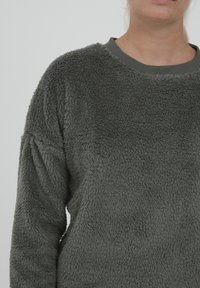 Sweatshirt in pile grigio scuro, con una superficie morbida e strutturata, scollatura rotonda a coste e spalle leggermente cadenti.