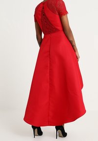 Röd kvällsklänning med spetsliv, korta ärmar och en svängande kjol. Bakdelen har knappar och dragkedja.