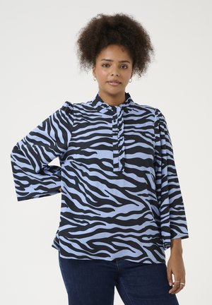Blouse à manches longues avec un motif zèbre noir et bleu clair, patte de boutonnage et col froncé. Tissu léger avec une coupe décontractée.