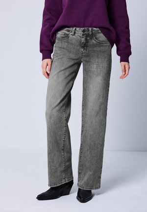 Grijze wijde denimjeans met een klassiek vijf-pocket ontwerp en subtiele vervaging. Gepaard met een paarse sweatshirt en zwarte hakken.