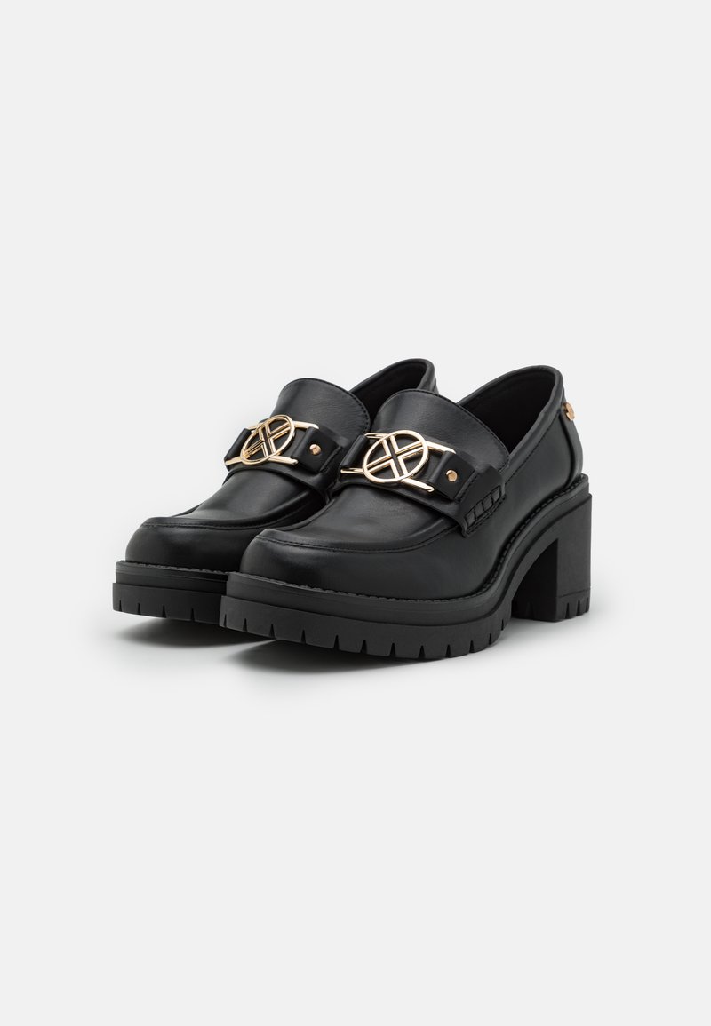 Scarpe platform nere con tacco chunky, presentano una finitura in pelle opaca, accessori in oro e una fascia decorativa sulla parte superiore.