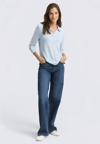 Šviesiai mėlyna ilgarankovė polo marškinėliai, laisvo kirpimo, derinami su tamsiai mėlynomis praplatintomis džinsais ir baltais sportbačiais. Lygus audinys, kasdieniškas stilius.