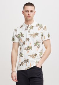 Hvit polo skjorte med tropisk palme tre mønster i grønn, brun og oransje, med krage og korte ermer.