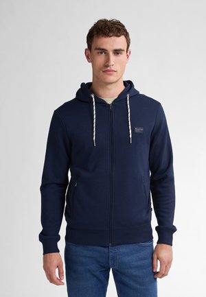 Navy blue zip-up hoodie made of soft fabric, featuring a drawstring hood, ribbed cuffs, and two side pockets with a small logo patch.