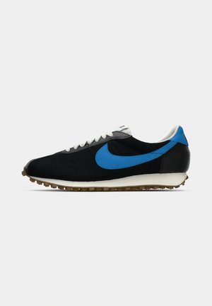 Chaussure de sport noire avec accents bleus, tige en tissu texturé, lacets blancs et semelle en caoutchouc avec des rainures de traction prononcées.