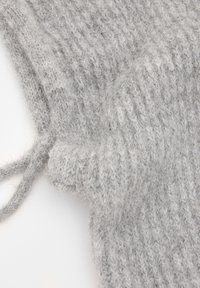 Grau gestrickter Stoff, der ein strukturiertes Muster mit einem weichen, flauschigen Aussehen zeigt. An einer Seite ist ein dünner Kordelzug sichtbar.