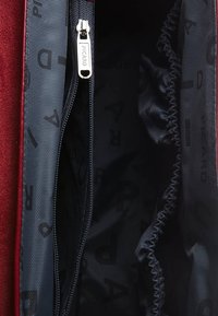 Unzipped dark gray bag compartment with elastic side pocket, silver zipper pull engraved with "PICARD," and red fabric edge.