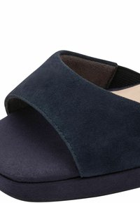 Sandale mule en daim bleu marine avec un bout ouvert, une large bride croisée et une semelle intérieure texturée et rembourrée pour le confort. Semelle plate, design minimaliste.