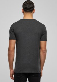 Camiseta de manga corta gris oscuro hecha de algodón suave, con un escote redondo y un corte relajado, mostrando la vista trasera sin patrones.