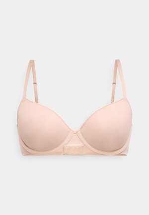 Μπεζ σουτιέν με επένδυση και μπανέλα, με ρυθμιζόμενες τιράντες και απαλό ύφασμα, εμφανίζεται μπροστά σε λευκό απλό φόντο.