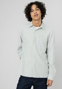 Chemise boutonnée vert clair avec des rayures bleues verticales. Elle possède une poche poitrine unique et des manches longues avec des poignets boutonnés.