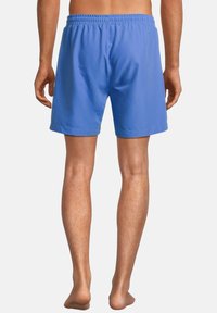 Siniset sortsit, jotka on valmistettu kevyestä kankaalta, jossa on joustava vyötärö. Suora malli päättyy polven ylle ja siinä on sileä pinta ilman koristeluja.