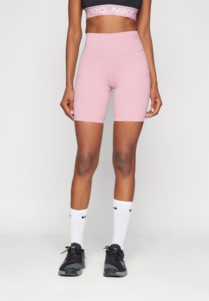 Light pink high-waisted bike shorts feature a smooth, stretchy fabric and seam detailing. Paired with black sneakers and white crew socks.