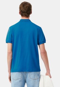 Polo a maniche corte in cotone blu brillante, con colletto classico, tinta unita e taglio pulito dell'orlo.