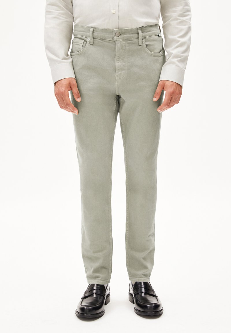 Pantalons en coton vert clair à coupe slim, design à cinq poches et fermeture à bouton. Associés à des chaussures en cuir noires.