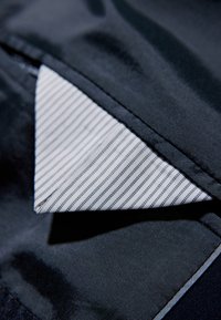 Granatowa tkanina o gładkiej teksturze, z kontrastującym białym wnętrzem kołnierza w cienkie pionowe paski. Czyste krawędzie.