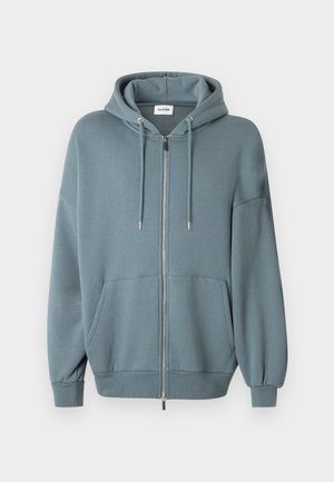 Sudadera con capucha y cremallera en tejido azul suave, con bolsillo delantero, capucha con cordón y puños acanalados para mayor comodidad y ajuste.