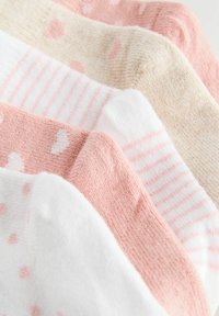 Vijf paar zachte babykousen van gebreide stof in pastelroze, wit en beige met strepen, stippen en hartjespatronen.