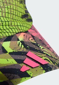 Neon grøn atletisk cap med et gittermønster, abstrakte design i pink og brun samt et fremtrædende pink Adidas-logo.