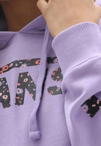 Felpa lilla con grafica a fiori sulla parte anteriore, dotata di cordino e polsini a costine. Dettaglio del tessuto morbido e testurizzato visibile.