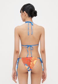 Set di bikini con top a fascia blu legato al collo e parte inferiore stampata multicolore con accenti arancioni e blu, realizzato in tessuto morbido.