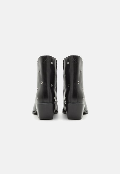 Botine din piele neagră, până la gleznă, cu vârf rotunjit, decorate cu gromete argintii și toc pătrat. Textură netedă și siluetă simplă.