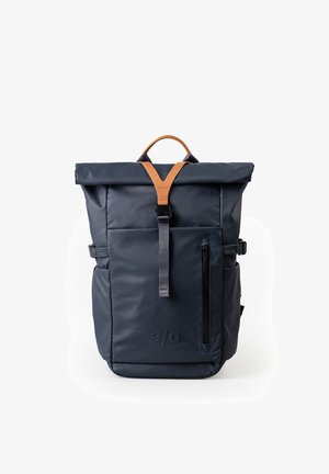 Dunkelblauer Rolltop-Rucksack mit beige-braunem Ledergriff, Front-Reißverschlusstasche und schwarzem Riemenverschluss auf weißem Hintergrund.