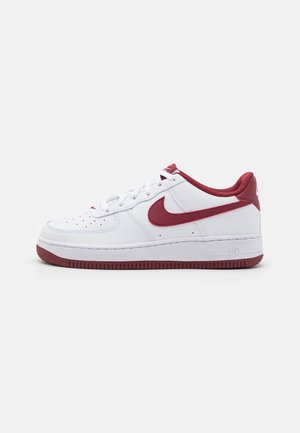 Zapatilla de cuero blanca con acentos en color burdeos. Caja de dedos perforada, suela de goma, cordones blancos y un logotipo prominente en el lado. Diseño clásico.