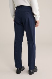 Marineblaue Baumwollhose mit glatter Textur, schlanker Passform, zwei Gesäßtaschen und dezentem Knopfdetail.