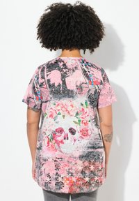 Multifarvet grafisk t-shirt med et blomsterkranie-design, primært i pink, med korte ærmer og en afslappet pasform.