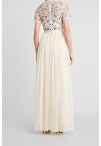 Maxikleid mit einem transparenten, bestickten Oberteil mit Blumenmuster. Der Rock ist cremefarben mit einer strukturierten Oberfläche und für mehr Volumen geschichtet.