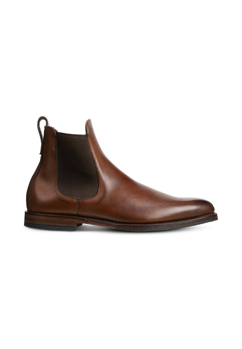 Bruine leren Chelsea-boot met elastische zijpanelen en een trekband. Glad oppervlak, spitse neus, lage gestapelde hak. Tijdloos ontwerp.