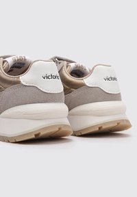 Sneaker color sabbia e beige con tomaia in suede e mesh, dettagli bianchi sul tallone e suola in gomma testurizzata. Marchio visibile sul tallone.