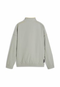 Veste gris clair avec col montant, ourlet élastique et poignets. Présente des coutures d'accent jaune le long des coutures. Le tissu semble lisse et légèrement texturé.