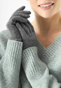 Graue Wollhandschuhe mit gerippten Bündchen und einer weichen Textur, kombiniert mit einem hellgrauen Pullover im V-Ausschnitt-Design.