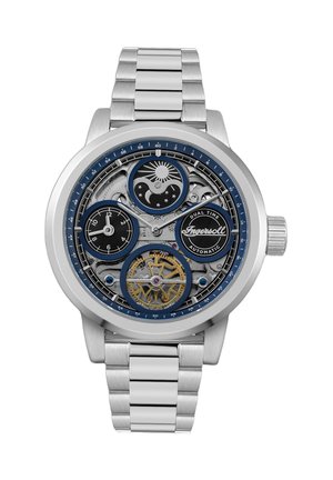 Montre automatique pour homme avec un bracelet en acier inoxydable argenté, un cadran bleu et noir, des engrenages exposés et des fuseaux horaires indiqués.