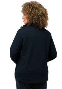 Tummansininen pitkähiha pullover, jossa on pystysuora kaulus, pehmeä puuvillasekoitekangas ja ommeltu sauma selässä lisäyksinä.