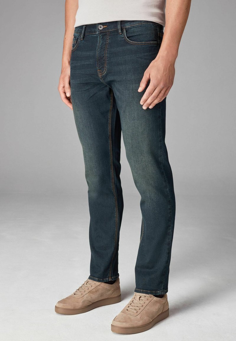 Sötétkék, slim fit farmernadrág, enyhe koptatással, narancssárga varrással, ötpocket dizájnnal, fém gombbal zárva.