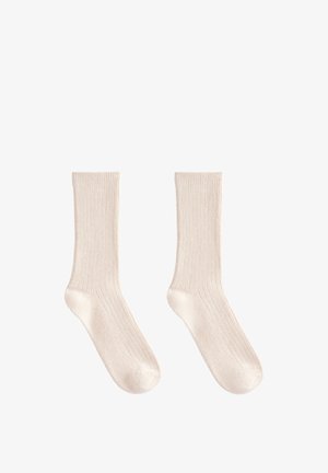 Chaussettes en coton beiges avec une texture côtelée, longueur mi-mollet, et finition lisse, dotées d'un design de pointe sans couture.