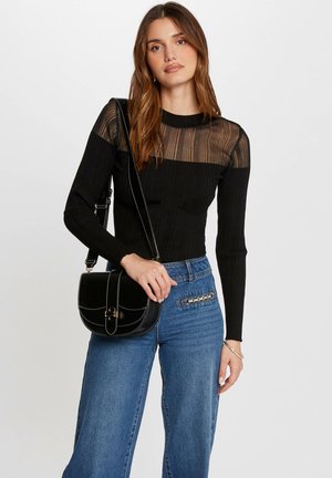 Black ribbed long-sleeve top with sheer striped design and high neckline, paired with high-waisted blue wide-leg jeans and a black crossbody bag.
