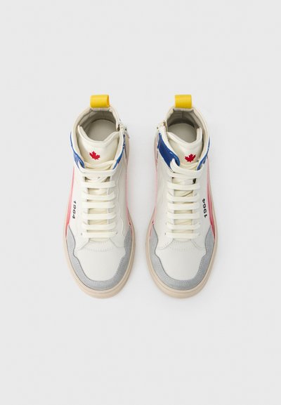 Αθλητικά παπούτσια τύπου high-top σε κρέμ απόχρωση με μπλε και κόκκινες πινελιές, γκρι σουέντ λεπτομέρειες, κίτρινη ταμπέλα στη φτέρνα και λευκά κορδόνια. Διαθέτουν λογότυπο και τη χρονιά '1964'.