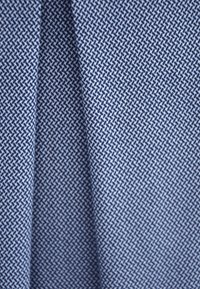 Woven fabric in blue tones featuring a geometric pattern with interlocking shapes. Smooth texture with a subtle sheen.