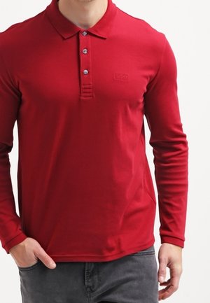 Polo de manga larga en algodón rojo brillante con cuello acanalado, tapeta de tres botones y un logo en relieve en el pecho.