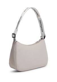 Μπεζ υφασμάτινη τσάντα ώμου με καμπυλωτό σχήμα, που διαθέτει λευκό λουρί με μαύρο κείμενο και ασημένιες μεταλλικές λεπτομέρειες στα σημεία σύνδεσης.