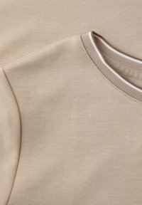 Beiger Strickpullover mit rundem Ausschnitt, der weiß- und braungestreifte Rippungen zeigt, mit Details an Schultern und Kragen.