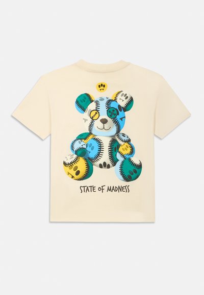 T-shirt de algodão creme com uma gráfica colorida de um urso. O urso é detalhado com padrões em azul, verde, amarelo e preto, com o texto "STATE OF MADNESS" abaixo.